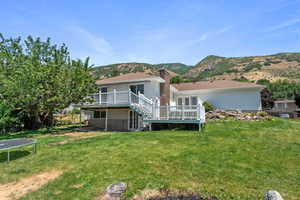 Rear view of property with a trampoline, a lawn, and a deck with mountain view