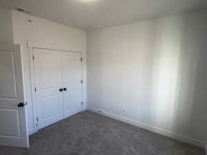 Unfurnished bedroom featuring a closet and dark colored carpet