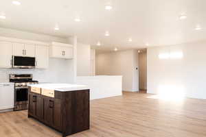 Kitchen featuring dark brown cabinets, appliances with stainless steel finishes, light wood-type flooring, and a center island