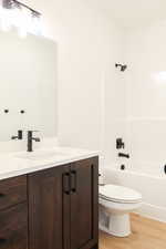 Full bathroom with wood-type flooring, vanity, toilet, and shower / bathing tub combination