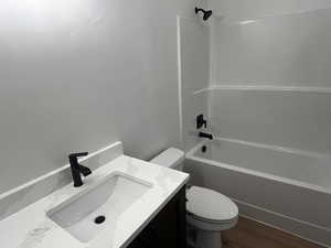 Full bathroom with toilet, hardwood / wood-style flooring, bathtub / shower combination, and vanity