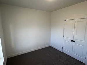 Unfurnished bedroom with a closet and dark carpet