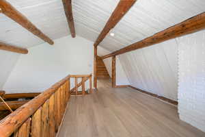 Additional living space featuring beam ceiling and hardwood / wood-style floors