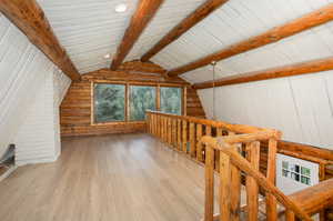 Bonus room featuring lofted ceiling with beams, log walls, and hardwood / wood-style flooring