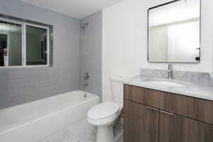 Full bathroom featuring vanity, tiled shower / bath, tile patterned floors, and toilet