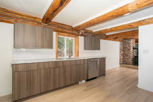 Kitchen featuring beamed ceiling, light hardwood / wood-style flooring, dishwasher, and light stone counters