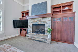 Carpeted living room featuring a fireplace with beautiful built-ins and a high ceiling