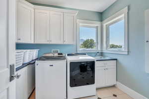 Laundry room featuring sink, separate washer and dryer, cabinets, and light tile patterned floors