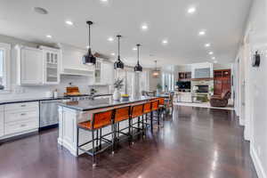 Kitchen with white cabinets, a breakfast bar, a kitchen island, decorative backsplash, and stainless steel dishwasher