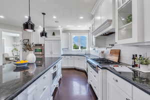 Kitchen with decorative backsplash, white cabinetry, and dark stone countertops