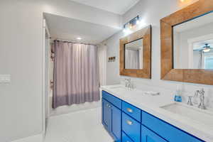 Bathroom featuring tile patterned flooring, shower / bath combo with shower curtain, double sink vanity, and ceiling fan