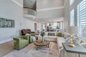 Living room featuring carpet floors, a high ceiling, crown molding, and a notable chandelier