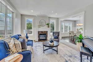 Living room with a premium fireplace, an inviting chandelier, a healthy amount of sunlight, and hardwood / wood-style floors