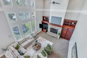 Living room featuring a fireplace, light colored carpet, and a high ceiling