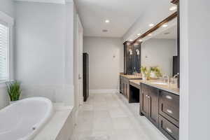 Bathroom with tiled bath, tile patterned floors, and double vanity