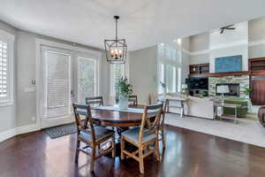 Carpeted dining space with a fireplace, ceiling fan with notable chandelier, a wealth of natural light, and a textured ceiling