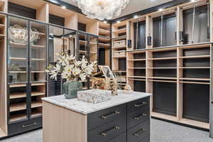 Walk in closet with carpet and an inviting chandelier