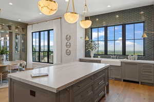 Kitchen with pendant lighting, decorative backsplash, light hardwood / wood-style floors, and sink