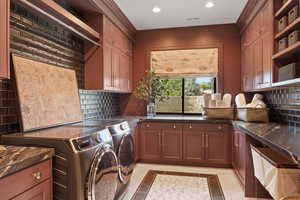 Interior space featuring light tile patterned flooring, washing machine and clothes dryer, and decorative backsplash