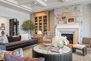 Living room with coffered ceiling, a fireplace, beam ceiling, and ornamental molding