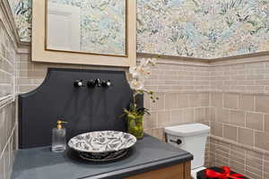 Bathroom featuring tile walls, toilet, and vanity