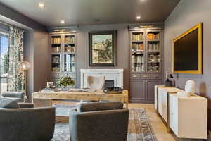 Living room with a high end fireplace and light hardwood / wood-style floors