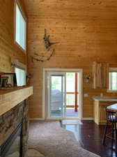 Entryway featuring dark hardwood / wood-style floors, a healthy amount of sunlight, a stone fireplace, and wooden walls