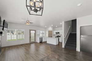 Living room with ceiling fan with notable chandelier, dark hardwood / wood-style flooring, sink, and a wealth of natural light