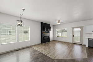 Unfurnished living room featuring ceiling fan with notable chandelier and hardwood / wood-style floors