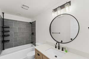 Full bathroom featuring vanity, tiled shower / bath combo, and toilet