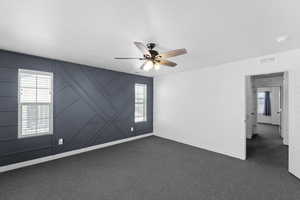 The primary bedroom with a wealth of natural light and a ceiling fan