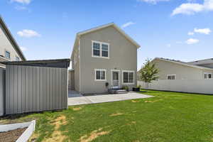 Rear view of house with shed,  lawn, and a patio area