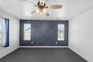 The primary bedroom features carpet flooring, a wealth of natural light, and a ceiling fan