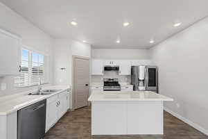 Kitchen featuring white cabinetry, dark hardwood / wood-style flooring, sink, a center island, and appliances with stainless steel finishes