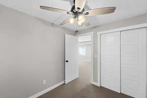 Basement bedroom featuring dark carpet, ceiling fan, and a closet