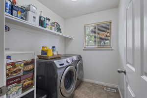 Laundry area featuring light tile patterned flooring and washer and dryer