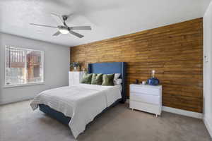 Bedroom featuring wooden walls, carpet floors, and ceiling fan