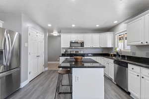 Kitchen with white cabinetry, sink, a center island, hardwood / wood-style floors, and appliances with stainless steel finishes