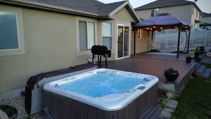 Wooden terrace featuring a hot tub and a gazebo