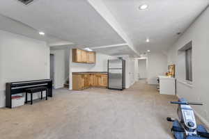 Carpeted living area featuring a kitchenette