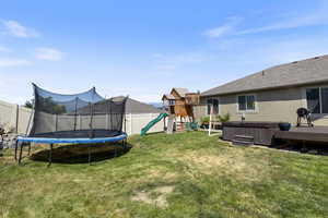 View of yard featuring a playground, a trampoline, and a hot tub