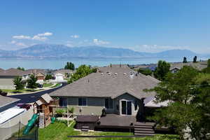 Back of property with a playground and a deck with mountain and lake view