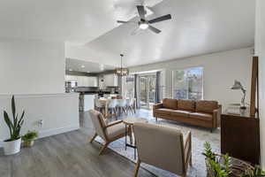 Living room featuring hardwood / wood-style floors, ceiling fan with notable chandelier, and lofted ceiling