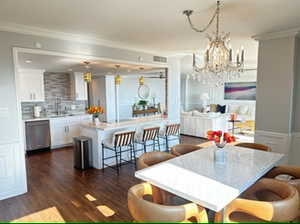 Dining room with crown molding, dark hardwood / wood-style flooring, sink, and a chandelier