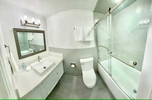 Full bathroom attached to second bedroom combined bath / shower with glass door, toilet, and vanity