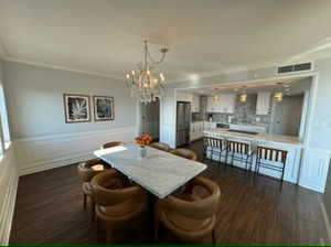 Dining room with crown molding, dark hardwood / wood-style flooring, chandelier.