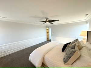 Primary bedroom with carpet flooring, ornamental molding, and ceiling fan. Left doorway shows attached bathroom.