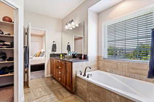 Bathroom with a relaxing tiled tub, vanity, and tile patterned flooring