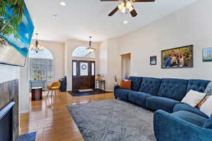 Living room featuring ceiling fan with notable chandelier, hardwood / wood-style flooring, and a tiled fireplace