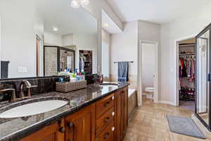 Bathroom featuring tile patterned flooring, toilet, an enclosed shower, and dual bowl vanity